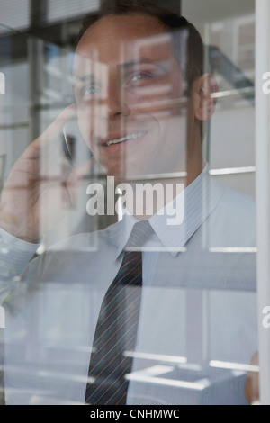 Ein Geschäftsmann telefonieren mit einem Handy über Fenster angezeigt Stockfoto