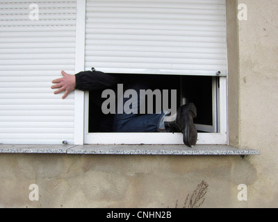 Ein Mann, der durch ein Fenster Klettern Stockfoto