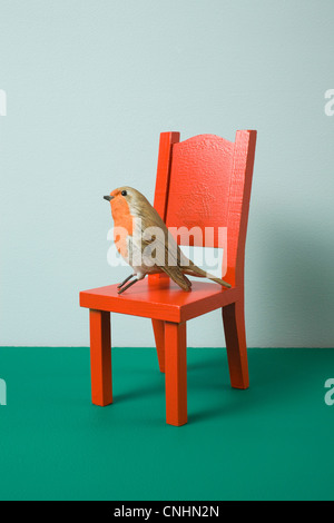 Eine Nachahmung Vogel sitzt auf einem Miniatur-Stuhl Stockfoto