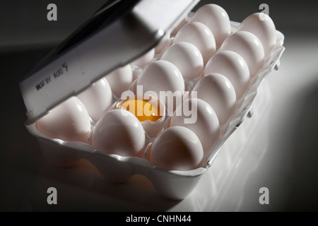 Eine gebrochene Ei und die Eigelb unter den Eiern pro Karton Stockfoto