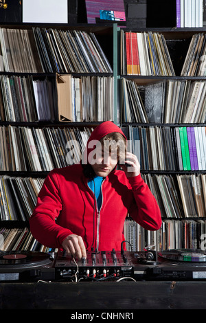 Ein junger Mann mit Decks und ein sound-Mixer in einem Plattenladen Stockfoto
