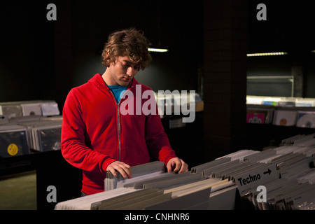 Ein junger Mann Suche durch Datensätze in einem abgedunkelten Plattenladen Stockfoto