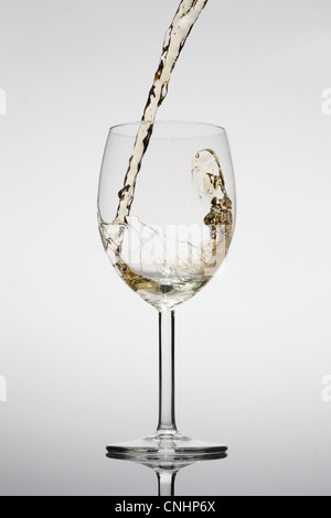 Weißwein wird in ein Glas gegossen Stockfoto