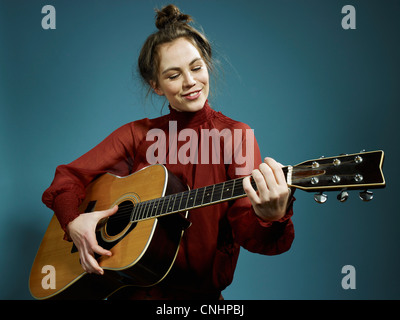 Eine junge Frau, die eine akustische Gitarre zu spielen Stockfoto