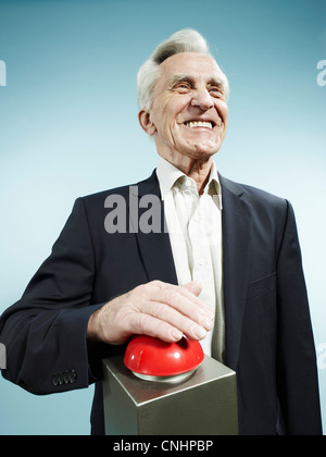 Ein grinsender senior Mann schob einen roten Gameshow-Summer Stockfoto