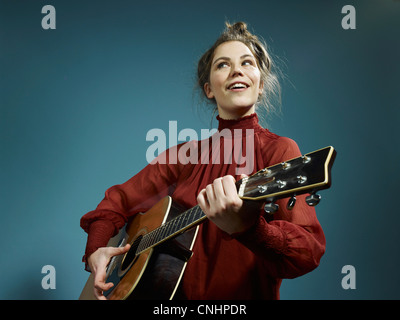 Eine junge Frau, die eine akustische Gitarre zu spielen Stockfoto