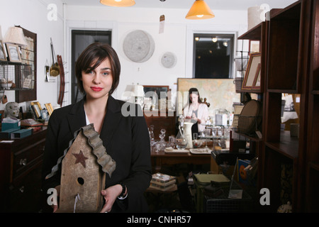 Eine Frau hält einen alten Vogelhaus in einem Antiquitäten-shop Stockfoto