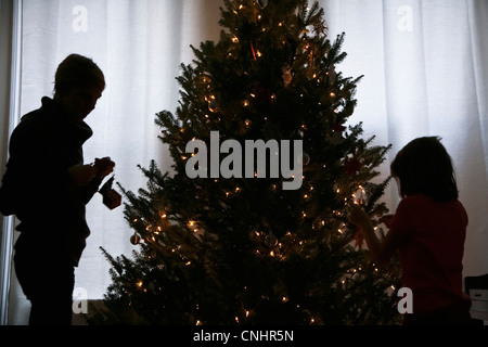 Silhouette von Mutter und Tochter einen Weihnachtsbaum zu verzieren Stockfoto