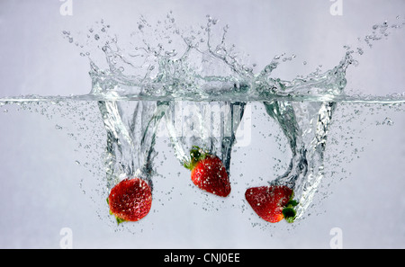 Erdbeeren, die ins Wasser fallen Stockfoto