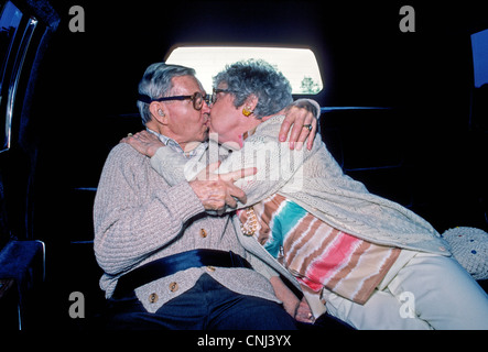 Ein älteres amerikanisches Ehepaar genießen einen Kuss auf dem Rücksitz einer Limousine auf dem Weg zu einer Feier für ihren 50. Hochzeitstag. Stockfoto