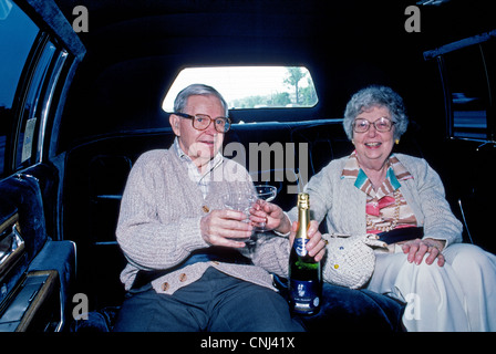 Ein älteres amerikanisches Ehepaar sind bereit, mit Champagner in einer Limousine auf dem Weg zu einer Feier für ihren 50. Hochzeitstag anstoßen. Stockfoto