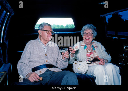 Ein älteres amerikanisches Ehepaar Toast mit Gläsern Champagner in einer Limousine auf dem Weg zu einer Feier für ihren 50. Hochzeitstag. Stockfoto