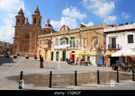 Springbrunnen spielen innerhalb der Stadtplatz in Marsaxlokk, während ein Tourist nehmen Sie ein Foto, Malta, Europa Stockfoto