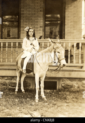 Kleines Mädchen im Matrosenanzug Ponyreiten Stockfoto