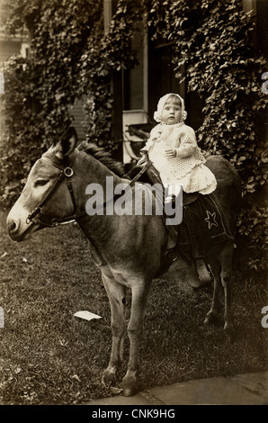 Infant Girl reitet einen Esel zu Hause Stockfoto