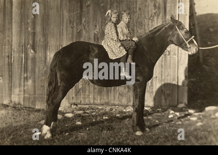 Bruder & Schwester auf einem einzigen Pferd im Stall Stockfoto