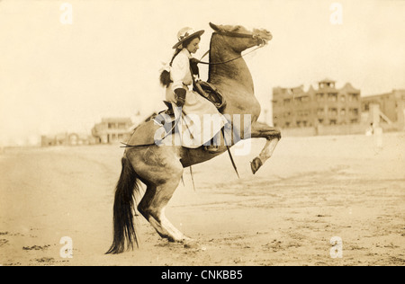 Cowgirl hängend auf eine Aufzucht Bronco am Strand Stockfoto