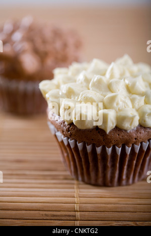 Lecker aussehende Schokolade Cupcake mit Vanille Zuckerguss auf Bambus Tischset-flacher Fokus Stockfoto