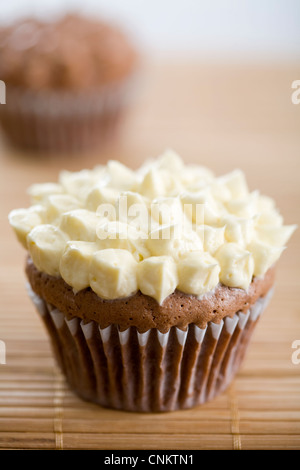 Lecker aussehende Schokolade Cupcake mit Vanille Zuckerguss auf Bambus Tischset-flacher Fokus Stockfoto
