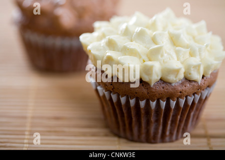 Lecker aussehende Schokolade Cupcake mit Vanille Zuckerguss auf Bambus Tischset-flacher Fokus Stockfoto