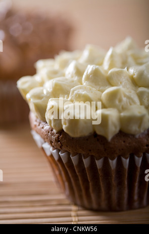 Lecker aussehende Schokolade Cupcake mit Vanille Zuckerguss auf Bambus Tischset-flacher Fokus Stockfoto