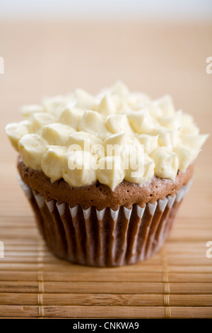Lecker aussehende Schokolade Cupcake mit Vanille Zuckerguss auf Bambus Tischset-flacher Fokus Stockfoto
