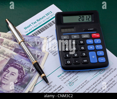 Britische Steuererklärung mit Taschenrechner, Kugelschreiber und Banknoten Stockfoto