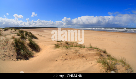 Sand und Meer in Holkham Bay an der North Norfolk-Küste. Zwei sehr weit entfernten Figuren am Strand. Stockfoto