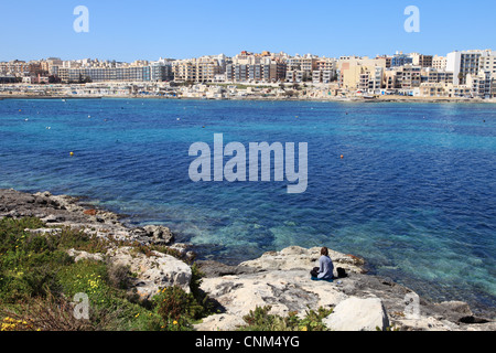 Junge Frau blickt auf die Mündung gegenüber den Touristenhotels in Qawra, Malta, Europa Stockfoto