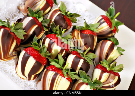 Weißer und brauner Schokolade überzogene Erdbeeren wirbelte auf Platte Stockfoto