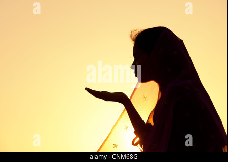 Indische Mädchen streckte ihre Hand tragen einen Sternen Schleier bei Sonnenuntergang. Silhouette. Indien Stockfoto