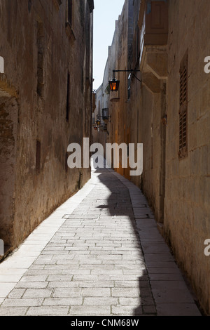 Eine typische schmale Gasse mit Sonnenlicht fangen das Glas in eine Straßenlaterne in Mdina Malta, Europa Stockfoto