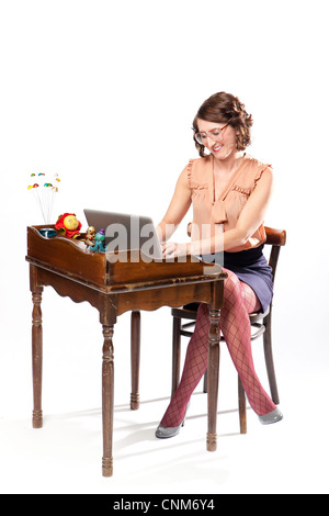 Eine Frau in Retro-Kleidung sitzt an einem Vintage Schreibtisch arbeiten. Stockfoto