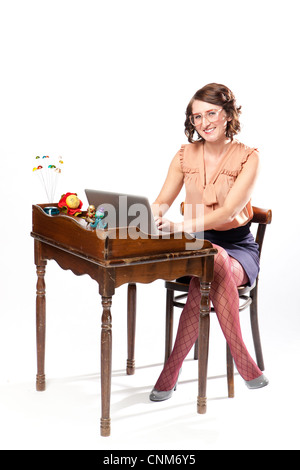 Eine Frau in Retro-Kleidung sitzt an einem Vintage Schreibtisch arbeiten lächelnd in die Kamera. Stockfoto