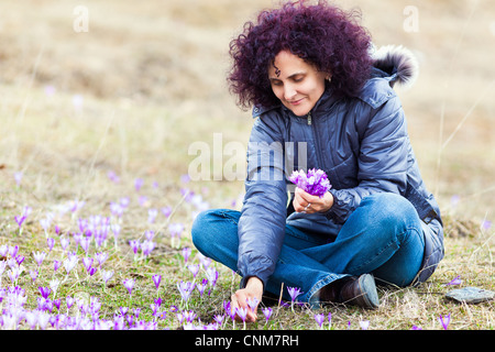 Ehrliches Porträt einer geschweiften rothaarige Frau Krokus Blumen auf einer Wiese zu pflücken Stockfoto