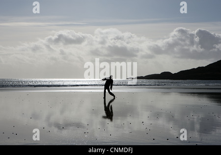 Teenager, die Silhouette und ein Frisbee zu werfen, an einem einsamen Strand Stockfoto