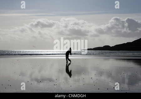 Teenager, die Silhouette und ein Frisbee zu werfen, an einem einsamen Strand Stockfoto