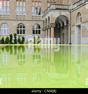 Zürcher Universitätsgebäude in einem gelben Wasserbecken reflektieren. Stockfoto