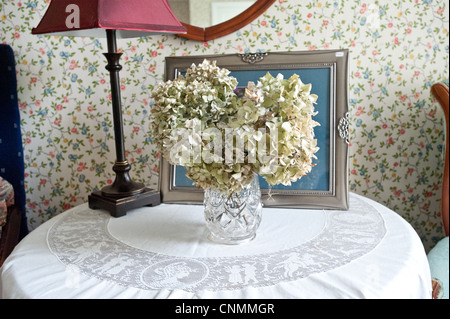 Blumenarrangement auf einem Nachttisch im Schlafzimmer möbliert mit Antiquitäten in einem Bauernhaus Bed And breakfast Stockfoto