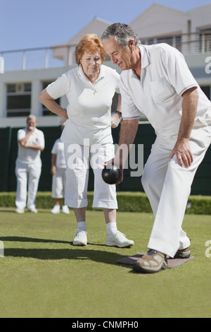 Man lehrt Frau Rasen-bowling Stockfoto