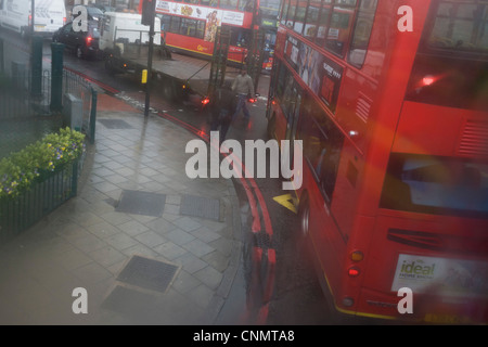 Luftaufnahme durch beschlagene Busfenster der roten Busse unten während der saisonalen Regen Regen. Stockfoto