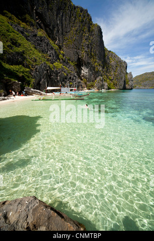 Outrigger Boote in einer kleinen Bucht vor der Küste steil Kalkstein des Tapiutan Island Bacuit Archipels, El Nido, Palawan, Stockfoto