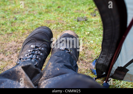 Nassen, schlammigen walking Stiefel und wasserdichte Hose getragen auf der Veranda eines Zeltes auf einem regnerischen Campingurlaub Stockfoto