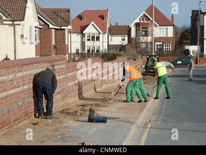 Des Rates Arbeiter wegräumen Dünen geblasen Strand auf Straße Bürgersteig Badeort Lytham St Anne's Lancashire England Stockfoto