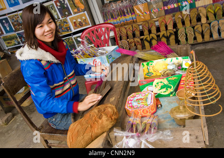 Horizontale Ansicht einer jungen vietnamesischen Frau machen Weihrauch oder Räucherstäbchen an ihrem Marktstand. Stockfoto