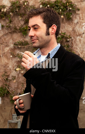 Mann Rauchen einer Zigarette in einem Garten. Stockfoto