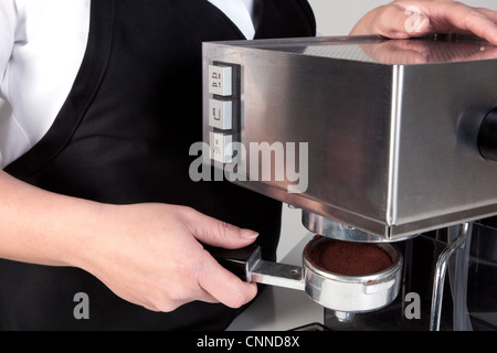 Foto von Barista setzen einen Porta-Filter voll von frisch gemahlenem Kaffee in einer Espresso-Maschine. Stockfoto