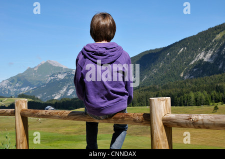 Rückansicht des jungen sitzen auf Holzzaun, Glieres Plateau, Alpen, Frankreich Stockfoto