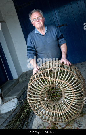 David Cotton, der letzte Hersteller von traditionellen Krabben / Hummer Töpfe in Mousehole, Cornwall, UK mit einem seine Töpfe. Stockfoto