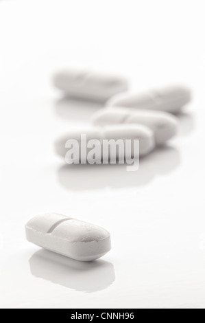 Weiße Raute geformte Tabletten auf eine weiße reflektierende Oberfläche Stockfoto